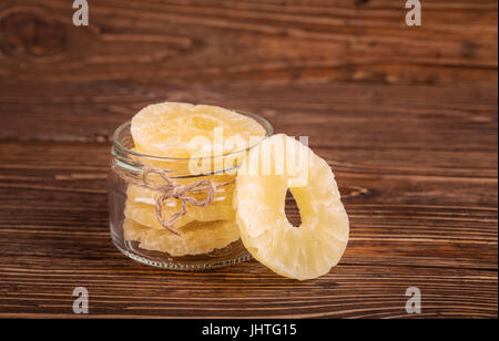 I canditi di ananas in un recipiente su un sfondo di legno Foto Stock