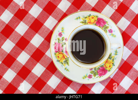 Tazza di tè nero in tazza vintage su rosso e bianco di panno a scacchi con spazio di copia Foto Stock