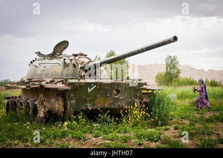 Una donna afghana tira le erbacce in un campo di patate da un vecchio arrugginito russo serbatoio militare nella valle di Bamyan lasciato dalla guerra contro l' Unione Sovietica Giugno 16, 2012 nella provincia di Mazar-i-Sharif, Afghanistan. (Foto di Ken Scar via Planetpix) Foto Stock