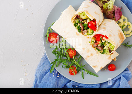 Shawarma da succosa carne di manzo, lattuga, pomodori, cetrioli, la paprika e la cipolla nel pane pita. Menù dietetici. Lay piatto. Vista superiore Foto Stock