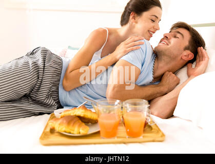 Coppia giovane sdraiato sul letto con colazione a letto Foto Stock