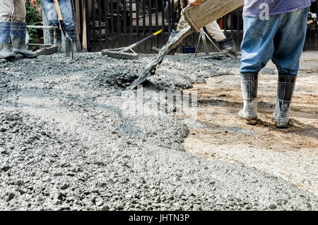 Gli uomini di colata di calcestruzzo fresco mix su strada Foto Stock