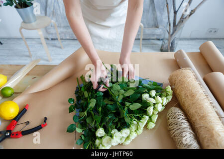 La donna rende bouquet sul tavolo Foto Stock