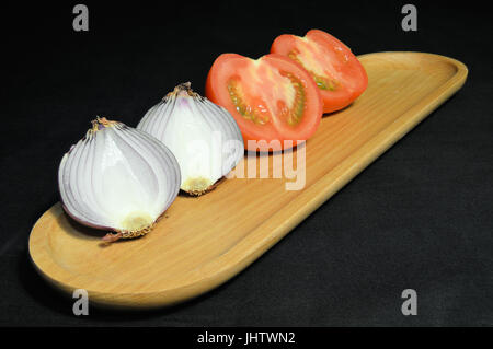 Cipolla e pomodoro tagliato a metà su legno vassoio/piastra Foto Stock