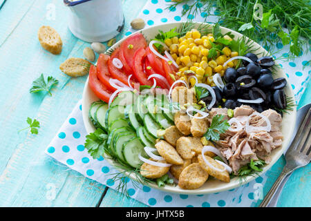 Insalata estiva con vinaigrette a base. Con insalata di tonno, verdure fresche, pistacchi e verdi su una cucina un tavolo di legno. Foto Stock