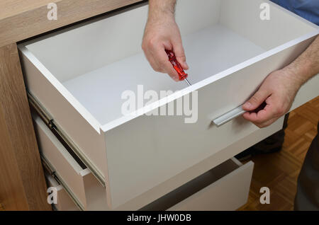 Uomo con le mani in mano il fissaggio di una maniglia di un cassetto Foto Stock