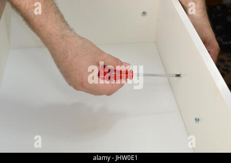 Uomo con le mani in mano il fissaggio di una maniglia di un cassetto Foto Stock