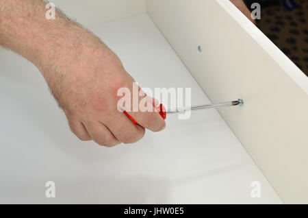 Uomo con le mani in mano il fissaggio di una maniglia di un cassetto Foto Stock