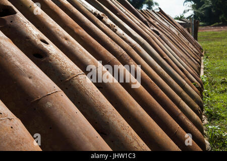 Deadly harvest lasciati dalla Guerra del Vietnam. Una parete di ruggine americana involucri bomba riciclato per l'uso in Xiangkhouang, Provincia, Laos Foto Stock