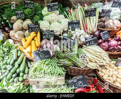 Pressione di stallo di ortaggi al mercato di Borough, Southwark, Londra Inghilterra. Wet aglio, stripey melanzane, fagiolini, asparagi, savoy cavoli cappucci, giallo di zucchine Foto Stock