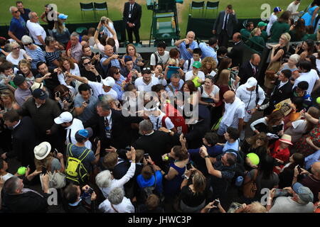 Roger Federer fa il suo modo attraverso una folla di spettatori a seguito di una sessione di formazione sulla giornata tredici dei campionati di Wimbledon al All England Lawn Tennis e Croquet Club, Wimbledon. Foto Stock