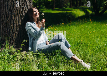 Bella giovane donna con il bianco tarassaco in posizione di parcheggio Foto Stock