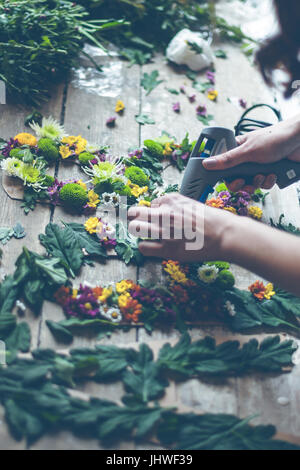 Fioraio effettuare decorazioni di fiori con lettere e colla. In interni luce naturale shot con piccole profondità di campo Foto Stock