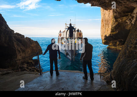 La costa della Sardegna turismo, due uomini preparare al dock di un tour in barca arrivando alla grotta di Nettuno a Capo Caccia vicino ad Alghero, Sardegna. Foto Stock