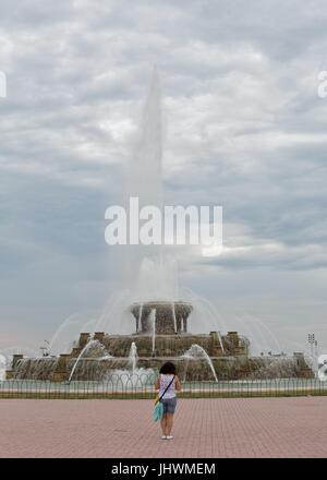 Una donna che guarda a Buckingham Fountain in Chicago, IL, Stati Uniti d'America. Foto Stock