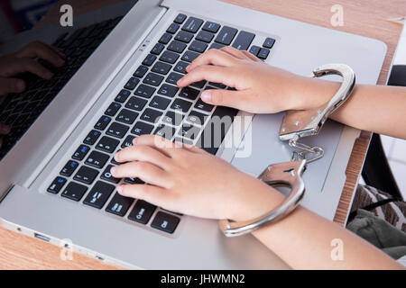 Bambino le mani in manette con il computer portatile in ufficio Foto Stock