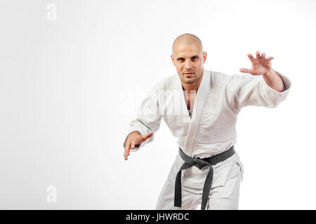 Giovane uomo lottatore in un kimono bianco con la cintura nera di judo, jujitsu pongono sulla isolato sfondo bianco Foto Stock