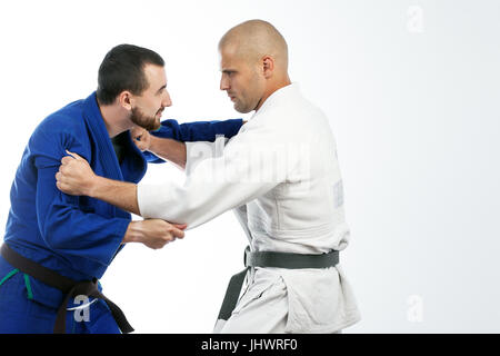 Due giovani uomini in blu e bianco kimono facendo un colpo di judo, lotta judo , jiu jitsu isolato su un fondo bianco Foto Stock