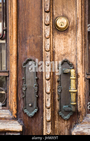 Primo piano di legno vecchio porta esterna con maniglie in ottone Foto Stock