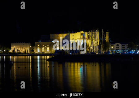 Vecchia stazione di potenza e il porto è illuminato di notte. Riva del Garda. Il lago di Garda. Italia Foto Stock