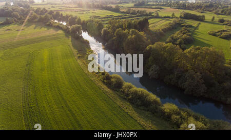 Vista aerea della curvatura del fiume attraverso i campi al tramonto. Foto Stock