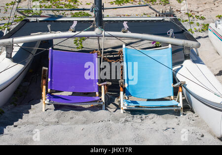 2 weathered sdraio in spiaggia tra gli scafi in catamarano su una spiaggia della Florida Foto Stock