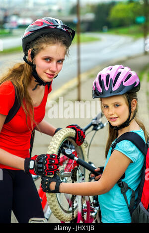 Pneumatico di una bicicletta per il pompaggio e la riparazione da bambino ciclista su strada . Foto Stock