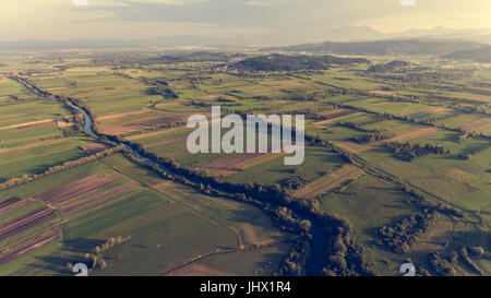 Vista aerea della curvatura del fiume attraverso i campi al tramonto. Foto Stock