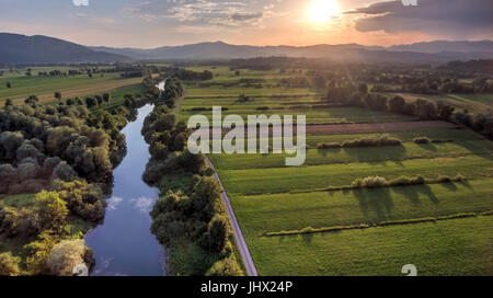 Vista aerea della curvatura del fiume attraverso i campi al tramonto. Foto Stock