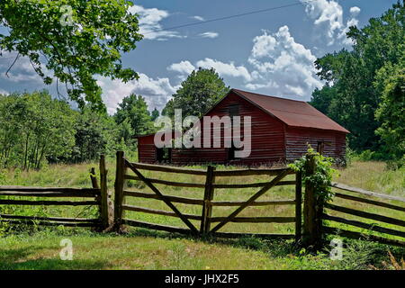 Un fienile rosso con cancello in legno si trova in un campo boscoso al George Washington Birthplace National Monument, Virginia Foto Stock