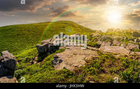 Enormi massi sul bordo della collina al tramonto. il bel tempo in estate paesaggio di montagna con arcobaleno Foto Stock