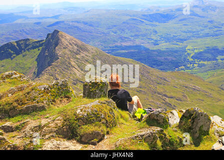 Persona godendo la vista dalla cima di Mount Snowdon, Gwynedd, Snowdonia, Galles del Nord, Regno Unito guardando verso sud-est Foto Stock