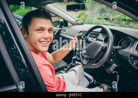 Quadriplegic uomo seduto nel sedile del suo controllo su Misura auto. Egli sorride per la fotocamera. Foto Stock