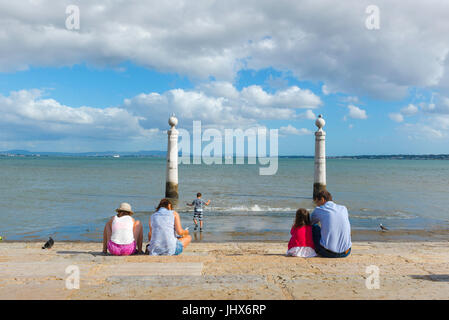 Famiglia al mare, in un pomeriggio d'estate una famiglia si rilassa in Cais das Colunas lungo il corso del fiume Tago a Lisbona, Portogallo. Foto Stock