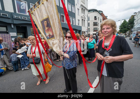 Londra, Regno Unito. Il 16 luglio 2017. Le donne con un banner che mostra Cristo attendere per prendere parte al corteo storico nella zona londinese di Clerkenwell dalla Basilica di San Pietro la Chiesa italiana. La processione annuale in onore del nostro Lday del Monte Carmelo ha avuto luogo ogni anno dal momento che è stato dato il permesso speciale nel 1883. Credito: Peter Marshall / Alamy Live News Foto Stock