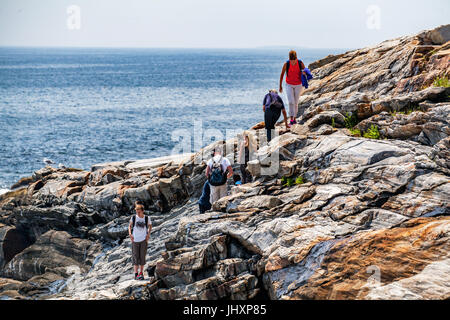 Una famiglia in vacanza si arrampica su rocce lungo la costa della Baia di Pemaquid a Bristol, Maine, Stati Uniti d'America. Foto Stock