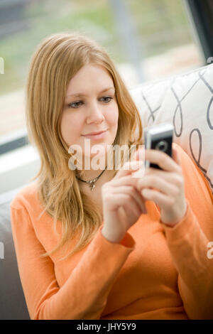 Giovane donna scrive SMS, Junge Frau schreibt SMS Foto Stock