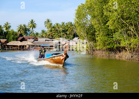 Tailandese tradizionale longtail boat accelerando lungo uno dei canali a est di Krabi town e il fiume, Provincia di Krabi, Thailandia. Foto Stock