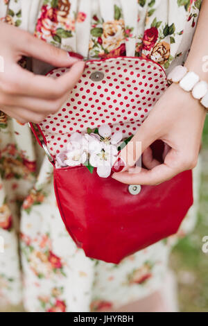 Vestito elegante. Close up di rosso trapuntato borsa in pelle borsetta nelle mani della donna elegante. Moda ragazza sulla strada. Giornata di sole. Moda femminile conce Foto Stock