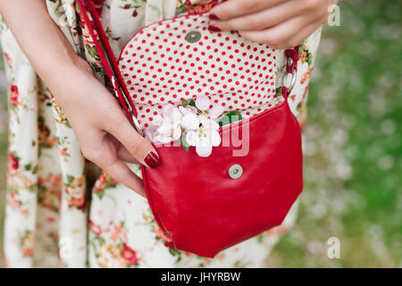 Vestito elegante. Close up di rosso trapuntato borsa in pelle borsetta nelle mani della donna elegante. Moda ragazza sulla strada. Giornata di sole. Moda femminile conce Foto Stock