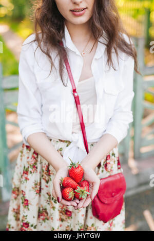 Donna in abito di fiori tenendo un mazzetto di fragole. Foto Stock