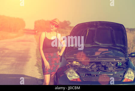 Donna con un ripartiti in auto in estate tramonto Foto Stock