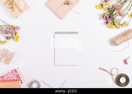 Aprire il notebook di carta si trova su un tavolo bianco con decorazioni, vista dall'alto Foto Stock