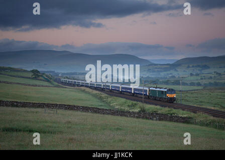 Il 2350 London Euston - Glasgow & Edinburgh Caledonian sleeper passa Salterwath (Shap Wells, Cumbria) appena prima del sorgere del sole in estate Foto Stock