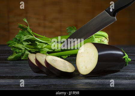 Affettare le melanzane sul bordo di legno con il coltello che