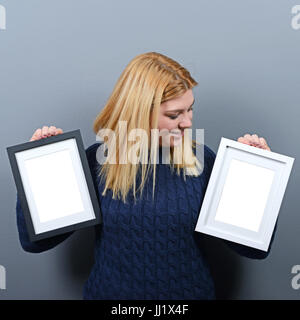 Ritratto di donna sorridente holding blank foto telai contro uno sfondo grigio Foto Stock