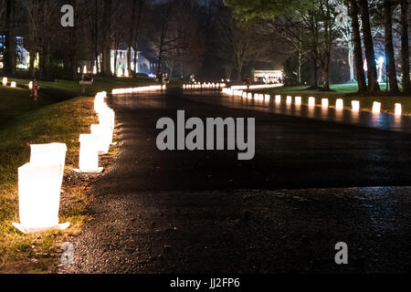 Burke, Stati Uniti - 24 dicembre 2016: la vigilia di Natale luci di candela in sacchi di carta di notte lungo la strada illuminata da case in neighborh residenziale Foto Stock