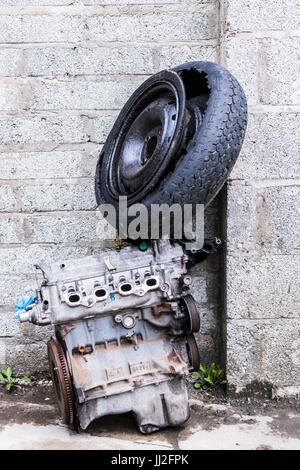 Il vecchio motore e auto ruota con pneumatico oggetto di dumping contro un vecchio breeze blocco di muro. Foto Stock