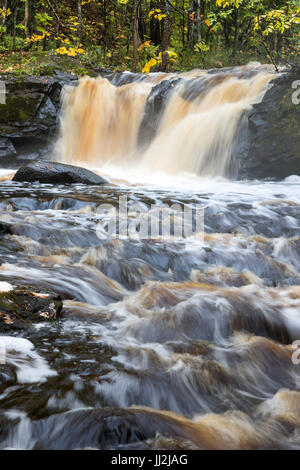 Radice birra cade a Wakefield Michigan nella Penisola Superiore del Michigan. Il tannino color acqua scorre sulla roccia e rovesciamento di liquidi nel torrente della piantatrice Foto Stock