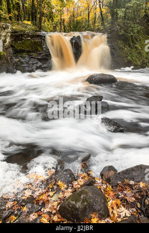 Radice birra cade a Wakefield Michigan nella Penisola Superiore del Michigan. Il tannino color acqua scorre sulla roccia e rovesciamento di liquidi nel torrente della piantatrice Foto Stock